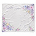 A personalized baby blanket featuring a watercolor floral design in pink, purple, and blue around the border, with the name 'Scarlett Blaise' in script and a numbered 1-12 month grid on a white background.