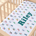 A personalized baby crib sheet with a colorful alphabet and animal print, featuring the name 'Riley' in large teal letters, shown fitted inside a light wood crib.