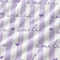 A close-up of a fabric surface with vertical lavender and white stripes, overlaid with repeated cursive 'amelia' text and small lavender hearts.