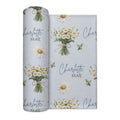 Personalized pale blue swaddle blanket with white daisy bouquets, scattered flowers, green leaves, and the name Charlotte Mae.