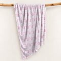 Personalized swaddle blanket hanging on a wooden rail with pink watercolor ballet slippers, bows and custom name Elizabeth.