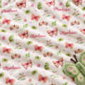 Personalized Butterfly and Flower Baby Girl Blanket. Pink, peach, and green butterflies flutter among flowers, leafy sprigs, and tiny hearts around a custom name.