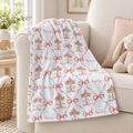 A soft blue throw blanket draped over a beige armchair in a nursery-like room, printed with a repeating pattern of coral bow outlines, carousel illustrations, and the word "emmy" in script.