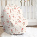 A baby car seat cover with a festive Christmas bunny print, styled on a white faux fur rug in front of a white wooden crib.