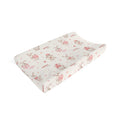 A baby changing pad with a curved contour shape, featuring a cream-colored fabric cover decorated with a pattern of sleeping cartoon bunnies in pink and brown, and small pink polka dots.