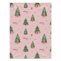 A personalized blanket featuring a repeating Christmas pattern of green watercolor trees, wrapped gifts, and gold stars on a soft pink background. The word 'CHARLOTTE' is printed in a cursive font next to the trees.