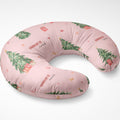 A U-shaped nursing pillow in light pink with a Christmas print featuring green trees, red gifts, and the text 'CHARLOTTE and'.