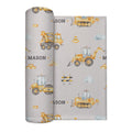 A rolled swaddle blanket with a construction-themed pattern featuring yellow construction vehicles, traffic cones, clouds, and the name 'MASON' on a light gray background.