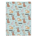 A personalized dog blanket featuring a repeating pattern of various cartoon dog illustrations, paw prints, bones, and the name 'Lacey' on a light blue background.