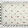 A personalized baby crib sheet featuring a repeating pattern of pink tutus, pink bows, gold rings, and green leaves on a pale sage green background. The text 'Avery GRACE' is printed in a dusty rose font, indicating a custom name combination.