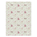 A personalized baby blanket with a repeating pattern of pink bows, gold rings, green leaves, and pink dresses, with the custom text 'Avery Grace' printed in dark red. The blanket is laid flat against a clean white background.