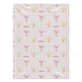 A rectangular fabric item, likely a blanket or towel, featuring a repeating pattern of gold crowns, pink bows, and the name 'Nadine' on a light pink and white striped background.