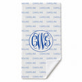A white personalized towel featuring a repeating blue 'CAROLINE' pattern and a large blue monogram 'CWG' in the center, with the bottom corner folded over to show the white reverse side.