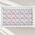 A baby crib mattress fitted sheet with a nautical pattern of starfish, anchors, shells, and the name 'Finley' repeated, shown inside a white wooden crib.