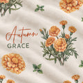 Closeup of a personalized lightweight fleece blanket with orange marigolds and Autumn Grace lettering on cream.