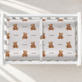 A top-down view of a white baby changing table containing a changing pad cover with a repeating pattern of small brown teddy bears and the word 'Rowan' printed underneath each bear.