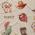 Western-themed fabric print featuring watercolor illustrations of a cowboy hat, red bandana, cactus with hat, money bag, boot, sheriff star, and the word 'SCOUT' on a beige background.