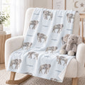 Pale blue Little Elephant blanket personalized with Cooper, draped over a cream rocking chair beside a plush elephant.
