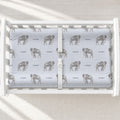Little Elephant changing pad cover with gray watercolor elephants and the name Cooper on pale blue, shown on a white changing table.
