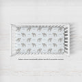A white wooden crib with a fitted sheet featuring a repeating pattern of gray elephants and the word 'Cooper' in gray text, photographed from above on a light textured floor.