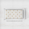 A white wooden crib with a fitted sheet featuring a repeating pattern of brown giraffes and the word 'Emerson' in brown text, shown from a top-down angle on a light textured floor.