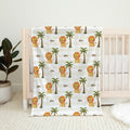 Little Lion personalized baby blanket with lions, palm trees, and the name Leo, displayed over a natural wood crib.
