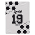 A white custom blanket featuring a black and white soccer theme. The design includes a classic black and white hexagonal soccer ball pattern in the top-left and bottom-right corners, with the text 'Henry', '19', and 'SOCCER' printed in black in the center.