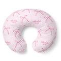 Blush pink nursing pillow cover with watercolor bows, tiny sparkles, and the name Charlotte Mae repeated in pink lettering.