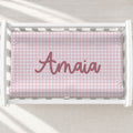 Personalized pink gingham baby changing pad cover with name Amaia centered.