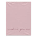 A rectangular light pink blanket with the name 'olivia grace' written in a delicate pink cursive script near the bottom, shown flat against a white background.