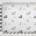 A personalized baby crib sheet with a repeating pattern of polar bears, seals, owls, and snowflakes, featuring the name 'Blake' in gray script. The sheet is displayed inside a white wooden crib.