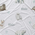 A white blanket or throw featuring a winter animal print with polar bears, an owl, a fox, seals, snowflakes, and the name 'Blake' in gray script.