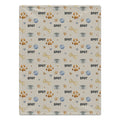 A rectangular dog blanket with a repeating dog-themed pattern featuring the word 'SPOT', paw prints, bones, bowls, and hearts on a light beige background.
