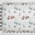 A baby crib bedding set featuring a white sheet with a repeating pattern of pastel race cars, trophies, checkered flags, and the name 'samuel' printed in gray.