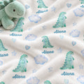 Personalized Sleepy Dinosaur Baby Blanket. Sleepy mint dinosaurs, soft blue clouds, stars, and hearts surround a custom name on a white background.