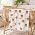 A personalized baby blanket with a cartoon owl pattern and the name 'Samantha' printed repeatedly, draped over a wicker bassinet in a bright nursery setting.