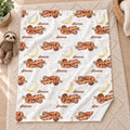 A fleece blanket with a custom print of sleeping brown sloths, yellow crescent moons, and the name 'Sienna' repeated in brown script, laid flat on a beige carpet next to a plush sloth toy.