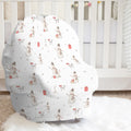 A baby car seat cover with a winter snowman pattern, displayed on a white baby crib in a nursery setting.