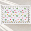 A white crib mattress fitted sheet with a colorful floral and leaf pattern, featuring the word 'Daisy' repeated in red script. The crib is shown from a top-down view on a light beige textured blanket.