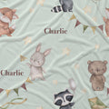 Personalized baby bedding set featuring a whimsical woodland animal print on a pale sage green background. The design includes watercolor-style illustrations of a fox, rabbit, raccoon, and teddy bear, accented with gold stars, bunting, and paper airplanes.