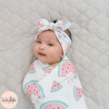 Baby wrapped in a pink watermelon pattern with a matching headband
