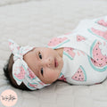 Baby wrapped in a pink watermelon pattern with a matching headband