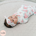 Baby wrapped in a pink watermelon pattern with a matching headband