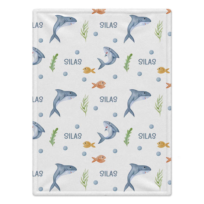 Personalized Shark Baby Blanket. Friendly watercolor sharks and colorful little sea details surround a custom name on a white background.