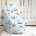 A custom baby car seat cover featuring a light blue background with a watercolor pattern of airplanes, mountains, clouds, and the names 'COLTON joseph' in brown, styled in a nursery setting on a white rug in front of a crib.