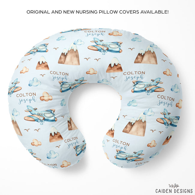 Personalized U-shaped nursing pillow cover featuring a light blue background with a repeating pattern of brown mountains, blue airplanes, clouds, and the text 'COLTON joseph'. The product is displayed on a clean white background with promotional text at the top and the brand logo 'CAIDEN DESIGNS' at the bottom right.