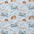 Personalized baby blanket with a repeating pattern of blue watercolor airplanes, brown mountains, beige clouds, and the name 'COLTON joseph' printed in brown and blue text on a white background.