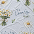 Personalized pale blue fabric with white daisy bouquets, scattered flowers, green leaves, and the name Charlotte Mae.