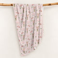 Blush pink swaddle blanket with pink gladiolus bouquets, scattered green leaves, and the name Audrey Jane repeated throughout.
