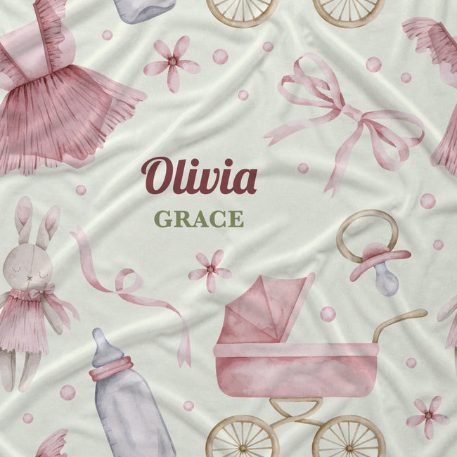 A personalized baby fabric featuring a watercolor-style print of pink bows, a bunny, a baby stroller, a pacifier, and a bottle on a cream background, with the text 'Olivia GRACE' in the center.